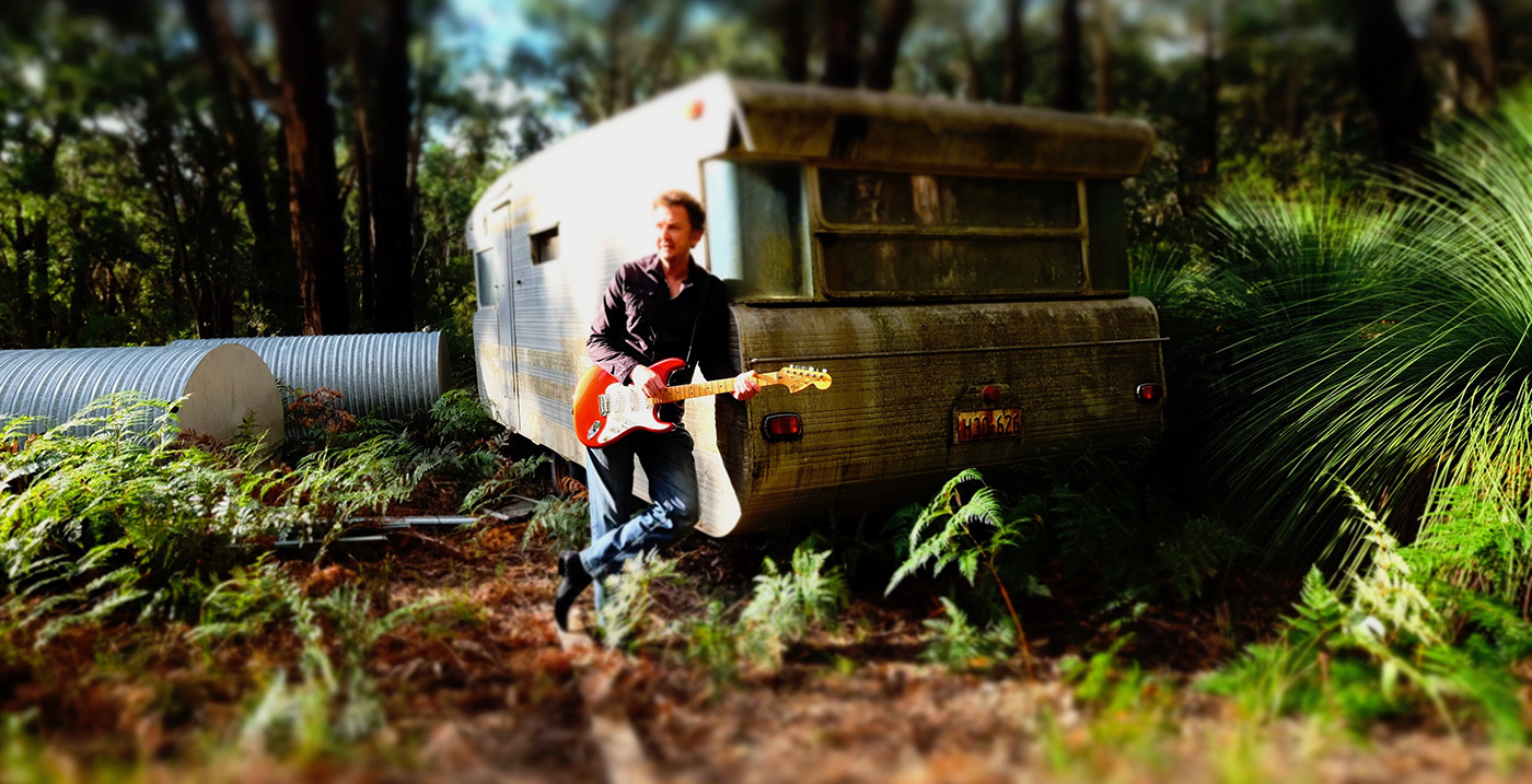 Patrick Shawcross with his guitar in the bush